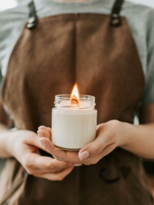Person in Brown Apron Holding Lighted Candle